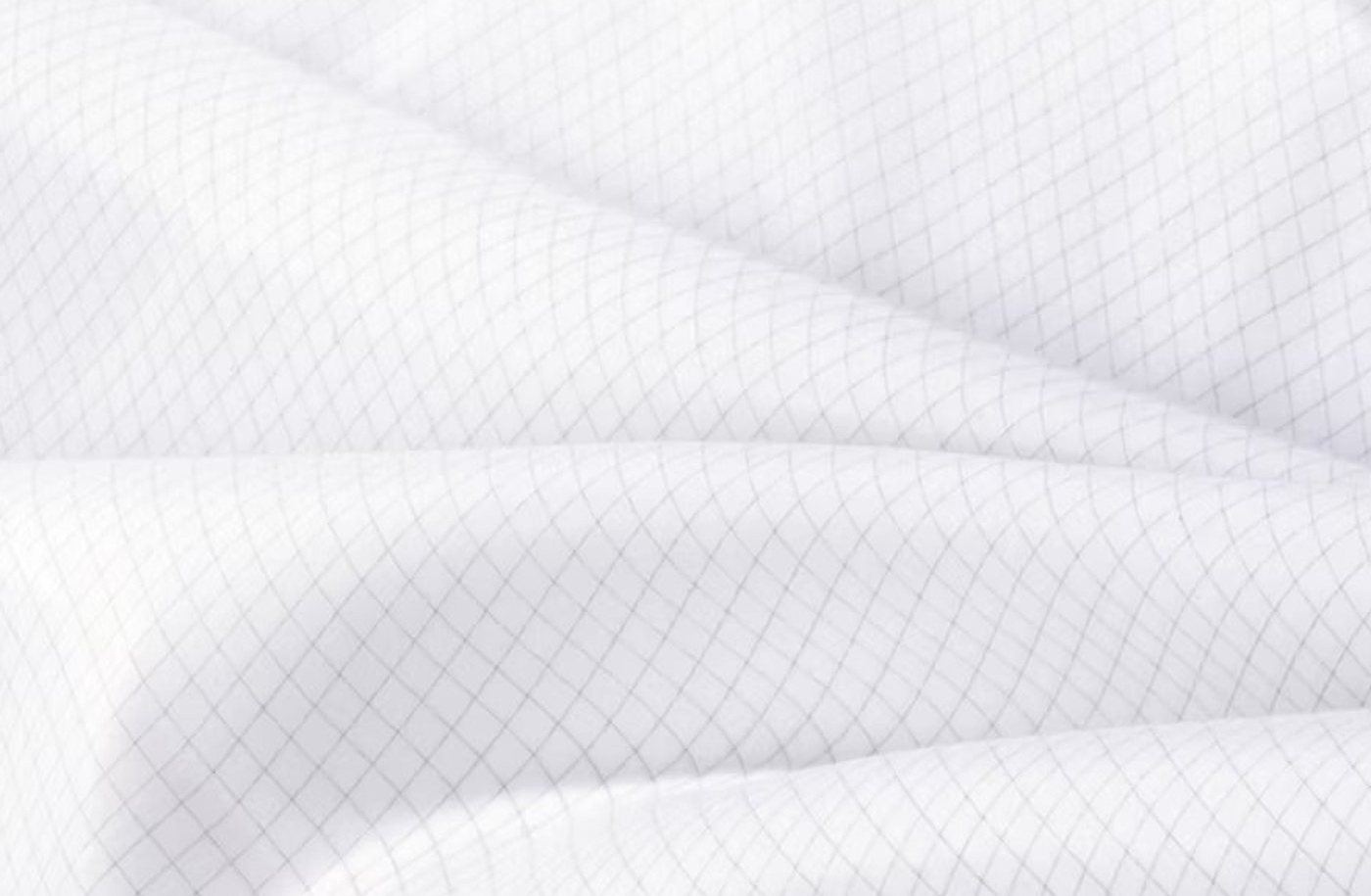 Großaufnahme des Allergocover-Gewebes: weiße dichtgewebte Mikrofaser mit einem feinen, gleichmäßigen Gitter aus dunklen Carbonfäden, eingewebt in Kett- und Schussrichtung.